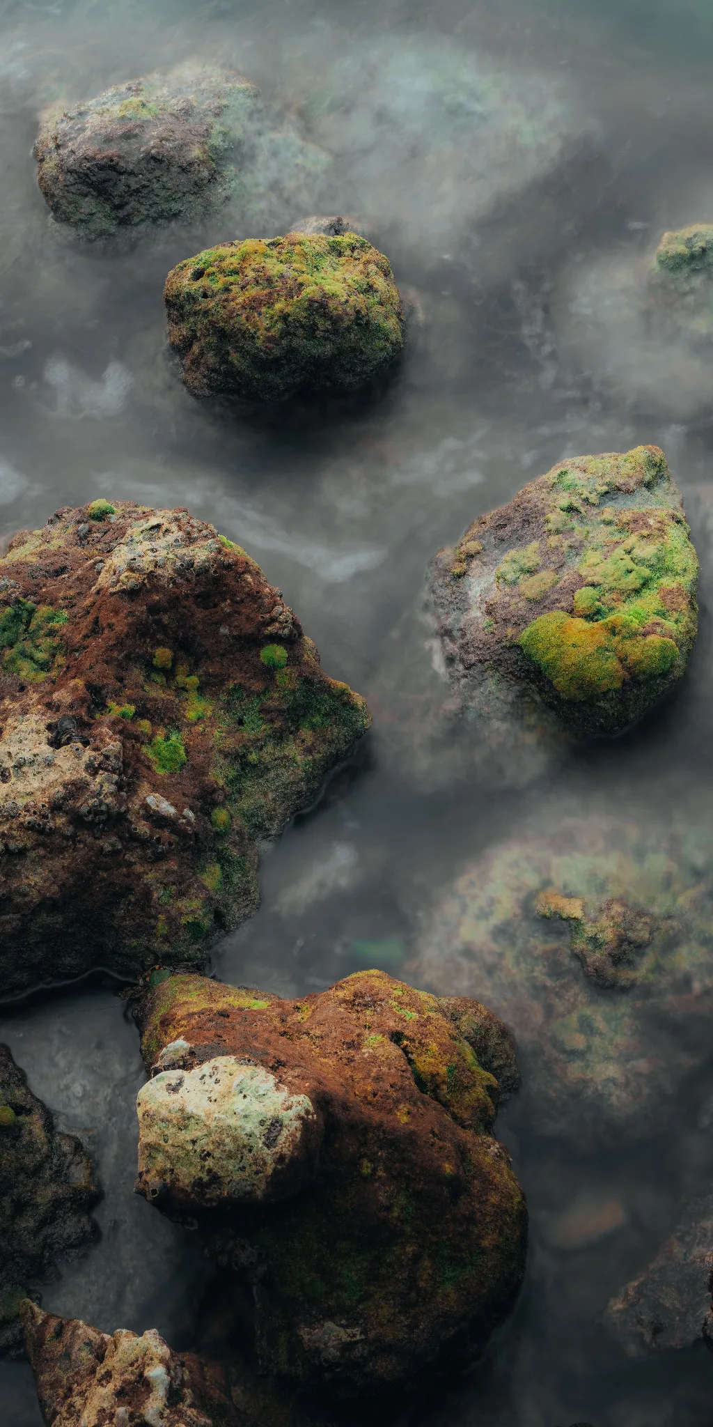 Rocce ricoperte di muschio emergono dall'acqua in movimento