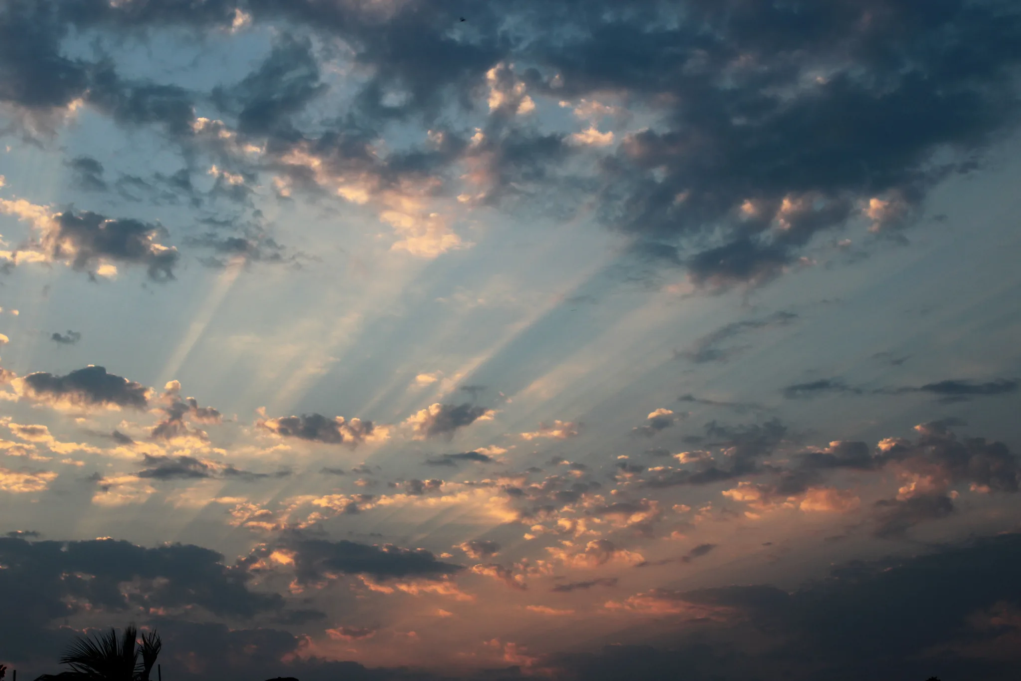 Raggi di luce attraversano un cielo ampio e nuvoloso