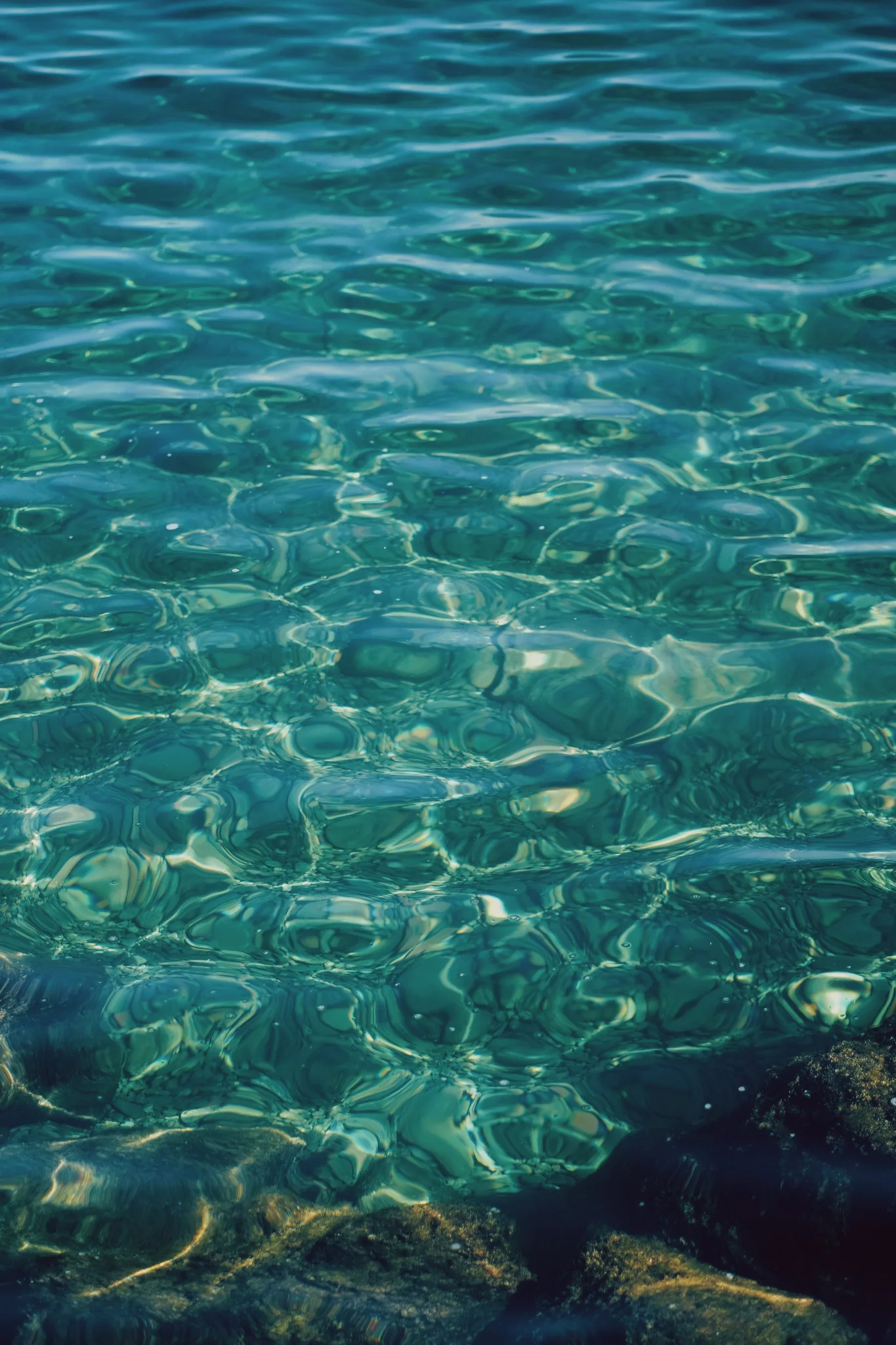 Acqua limpida attraversata da riflessi turchesi sopra le pietre